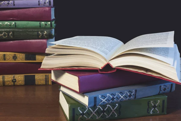 Eski açık ders kitabıyla kütüphanede kitap, okuma masasında edebiyat metin arşivi yığını ve akademik eğitim öğrenme kavramı için okul çalışma odası arka planındaki kitaplıklar.