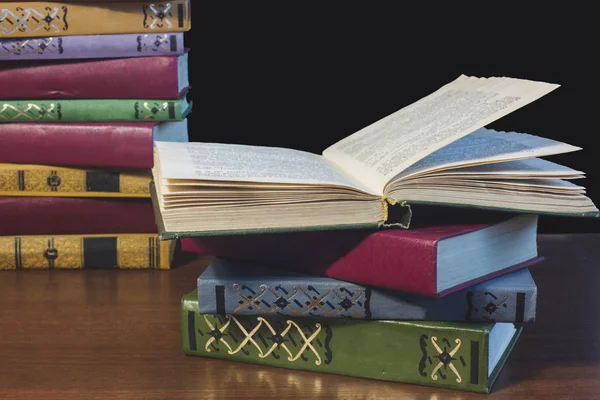 Eski açık ders kitabıyla kütüphanede kitap, okuma masasında edebiyat metin arşivi yığını ve akademik eğitim öğrenme kavramı için okul çalışma odası arka planındaki kitaplıklar.