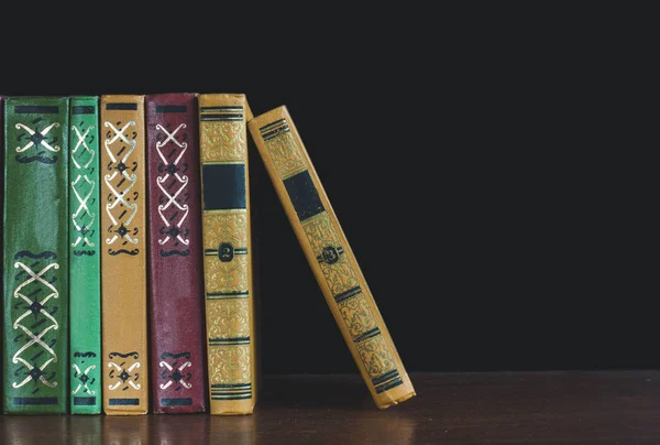 Eski açık ders kitabıyla kütüphanede kitap, okuma masasında edebiyat metin arşivi yığını ve akademik eğitim öğrenme kavramı için okul çalışma odası arka planındaki kitaplıklar.