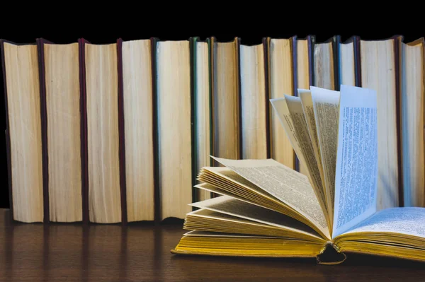 Eski açık ders kitabıyla kütüphanede kitap, okuma masasında edebiyat metin arşivi yığını ve akademik eğitim öğrenme kavramı için okul çalışma odası arka planındaki kitaplıklar.