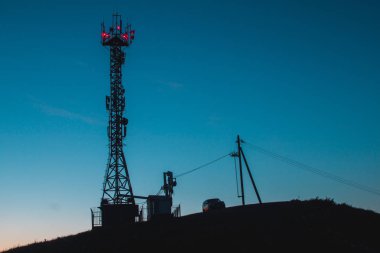 Gün batımında telekomünikasyon Kulesi. Ve dağda araba. Gece