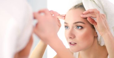 Genç ve sağlıklı bir kadının yüzü ve aynadaki yansıması.