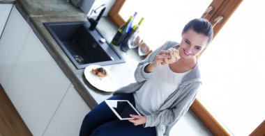 Mutfakta dijital tablet kullanan güzel genç bir kadın..