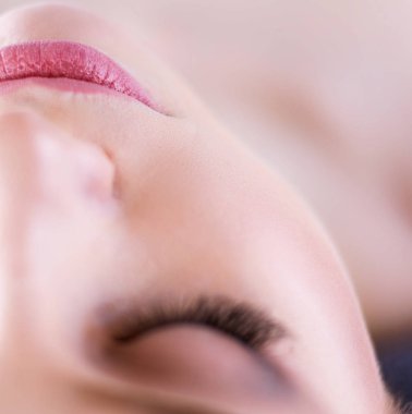 Masaj masasında uzanmış gözleri kapalı rahatlayan genç bir kadın. - Kadın. Spa salonu