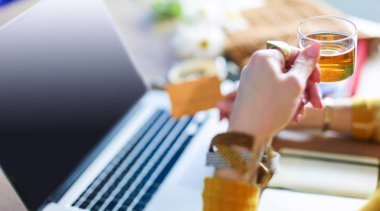 Genç bir kadın kahve molasında ya da kahve molasında dizüstü bilgisayar kullanıyor.