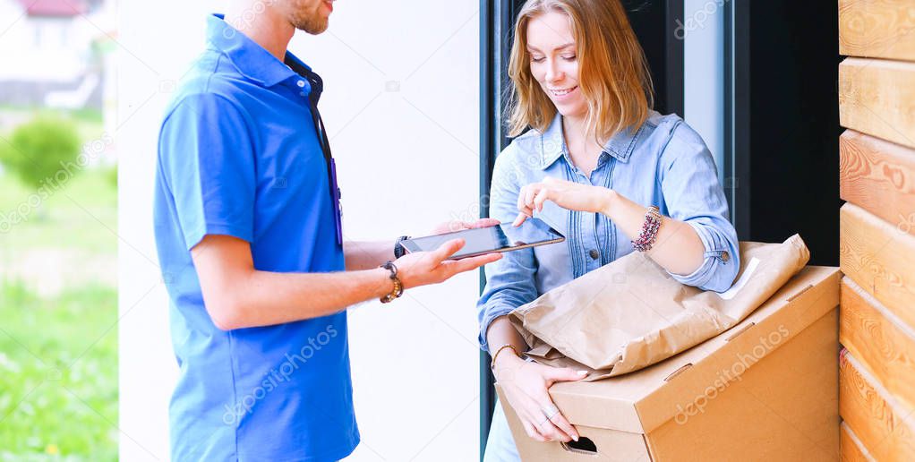 Smiling delivery man in blue uniform delivering parcel box to recipient - courier service concept. Smiling delivery man in blue uniform