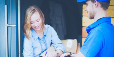 Mavi üniformalı gülümseyen kurye servis konseptine paket kutusu teslim eden teslimatçı. Mavi üniformalı gülümseyen teslimatçı.