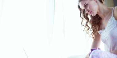 Dizüstü bilgisayar ile yatakta oturan genç güzel kadın.