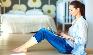 Çocuk karyolası dizüstü bilgisayar ile yakın katta oturan bir genç bayan. Genç anne