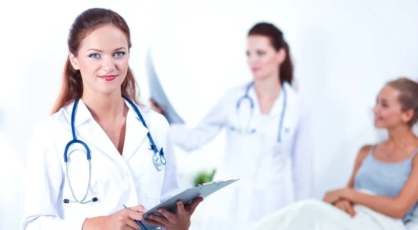 Médico sonriente con una carpeta en uniforme de pie en el hospital — Foto de Stock