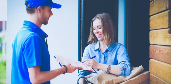 Uśmiechnięty dostawca w niebieskim mundurze dostarczający skrzynkę odbiorcy - koncepcja usługi kurierskiej. Uśmiechnięty kurier w niebieskim mundurze — Zdjęcie stockowe