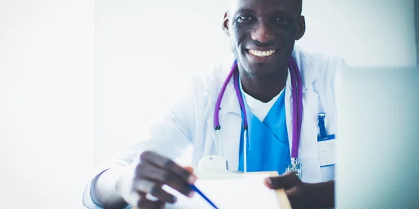 Portrait of young male doctor wearing headset while using computer at desk in clinic. Doctor. — Stock Photo, Image