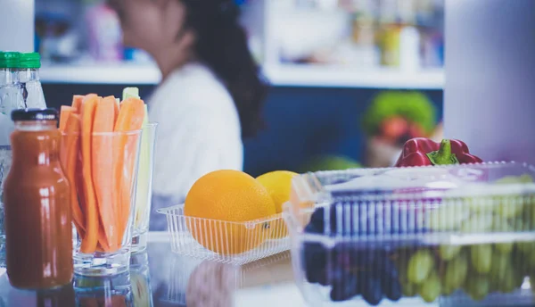 Portrait of female standing near open fridge full of healthy food, vegetables and fruits. Portrait of female — Stock Photo, Image