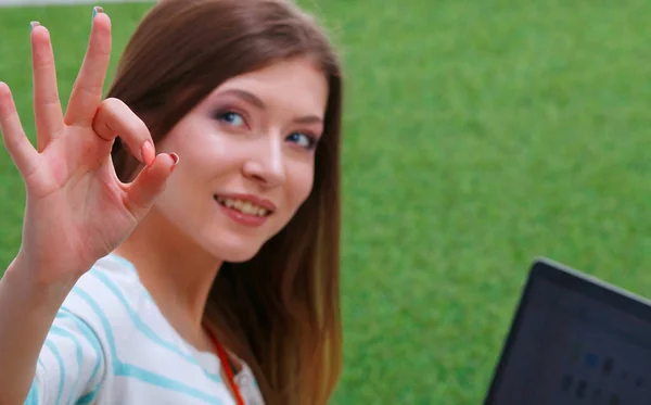 Mujer joven con portátil sentado en la hierba verde. Portreit mujer joven —  Fotos de Stock