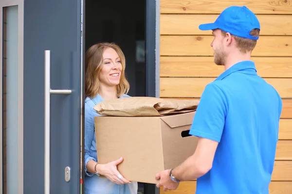 Uomo di consegna sorridente in uniforme blu che consegna pacchi al destinatario concetto di servizio di corriere. Uomo sorridente consegna in uniforme blu — Foto Stock