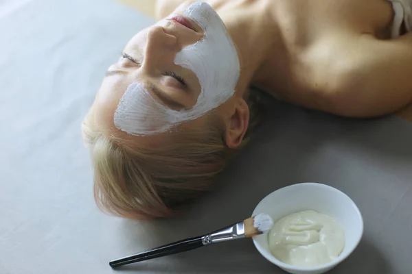 Gezichtsmasker. Mooi jong meisje in spa, schoonheidsspecialist vrouw gezicht masker toe te passen. — Stockfoto