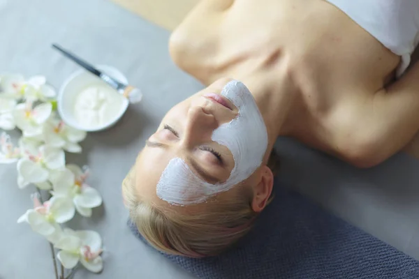 Gezichtsmasker. Mooi jong meisje in spa, schoonheidsspecialist vrouw gezicht masker toe te passen. — Stockfoto