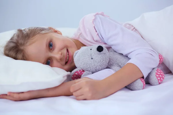 Kleines Mädchen schläft im Bett mit einem Spielzeug-Teddybär. — Stockfoto