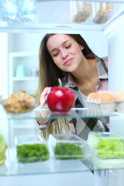Retrato de fêmea em pé perto da geladeira aberta cheia de alimentos saudáveis, legumes e frutas. Retrato de fêmea — Fotografia de Stock