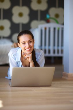 Çocuk karyolası dizüstü bilgisayar ile yakın katta oturan bir genç bayan. Genç anne