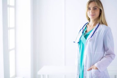 Genç bir kadın doktorun portresi, elinde aipad ile, bir tıp ofisinde.