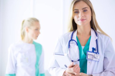 Genç bir kadın doktorun portresi, elinde aipad ile, bir tıp ofisinde.