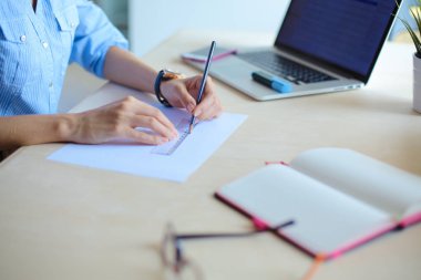 Ofis masasında dizüstü bilgisayarla oturan genç bir kadın. Genç bir kadın. Dizüstü bilgisayar