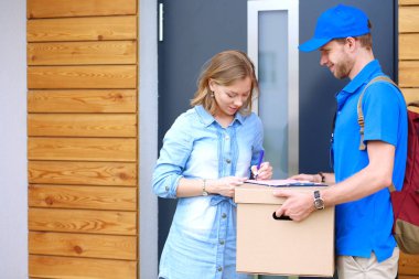 Mavi üniformalı gülümseyen kurye servis konseptine paket kutusu teslim eden teslimatçı. Mavi üniformalı gülümseyen teslimatçı.