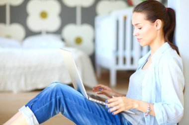 Çocuk karyolası dizüstü bilgisayar ile yakın katta oturan bir genç bayan. Genç anne