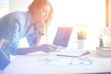 Ofis masasında oturan ve cep telefonuyla konuşan genç ve güzel bir iş kadını. İş kadını