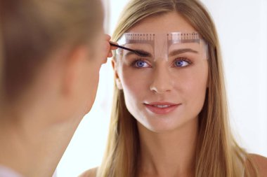Kaşlar için kalıcı makyaj. Güzellik salonunda kalın kaşlı güzel bir kadın..