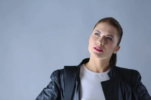 Portret van mooie jonge brunette vrouw in stijlvol zwart jasje op grijs. — Stockfoto