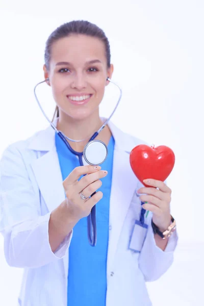 Medico femminile positivo in piedi con stetoscopio e simbolo del cuore rosso isolato. Donna medico — Foto Stock