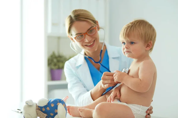 Ženský doktor poslouchá dítě se stetoskopem na klinice — Stock fotografie