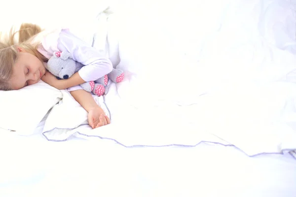 Gyermek kislány alszik az ágyban, egy játék mackó. — Stock Fotó