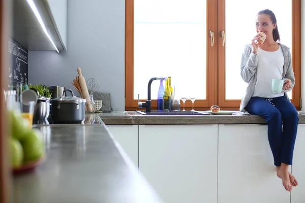 Hermosa joven usando una tableta digital en la cocina. — Foto de Stock