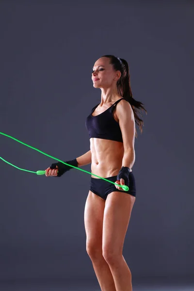 Muskulöse junge Frau, die auf grauem Hintergrund steht. muskulöse junge Frau. schönes Mädchen beim Seilspringen — Stockfoto