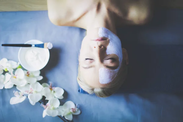 Masque visage.Belle jeune fille au spa, femme cosmétique appliquant un masque facial . — Photo
