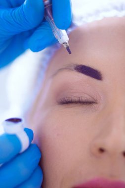 Kaşlar için kalıcı makyaj. Güzellik salonunda kalın kaşlı güzel bir kadın..