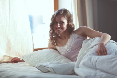 Pencere yakınındaki erken sabah yatakta yatan kadın.