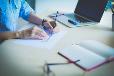 Ofis masasında dizüstü bilgisayarla oturan genç bir kadın. Genç bir kadın. Dizüstü bilgisayar
