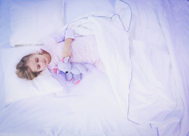 çocuk oyuncak oyuncak ayı ile yatakta uyur küçük kız.