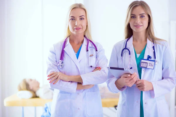 Портрет трьох впевнених жінок-лікарів, що стоять з обіймами, схрещеними в медичному кабінеті . — стокове фото