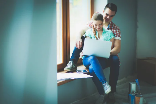 Retrato de jovem casal em movimento em nova casa sentado com laptop — Fotografia de Stock