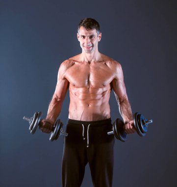 Yakışıklı kaslı adam dumbell ile çalışma dışarı. Kişisel fitness eğitmeni. Kişisel eğitim.