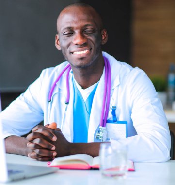 Masada dizüstü bilgisayarla çalışan genç bir Afrikalı doktor. Doktor bey. İşyeri