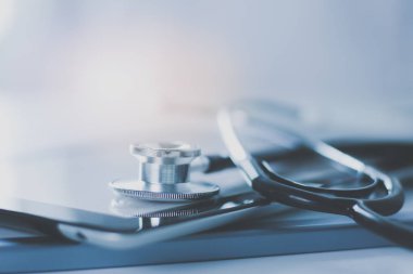 Tıbbi ekipman: Beyaz arka planda mavi steteskop ve tablet. Tıbbi ekipman