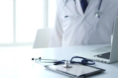 Tıbbi ekipman: Beyaz arka planda mavi steteskop ve tablet. Tıbbi ekipman