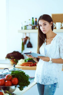 Mutfağında yemek için bir tablet bilgisayar kullanan genç kadın. Genç kadın .