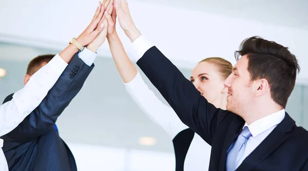 Business team joining hands together standing in office — Stock Photo, Image